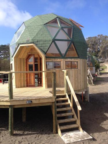 a house with a green roof on a wooden deck at Dune & Domes Pichilemu in Pichilemu