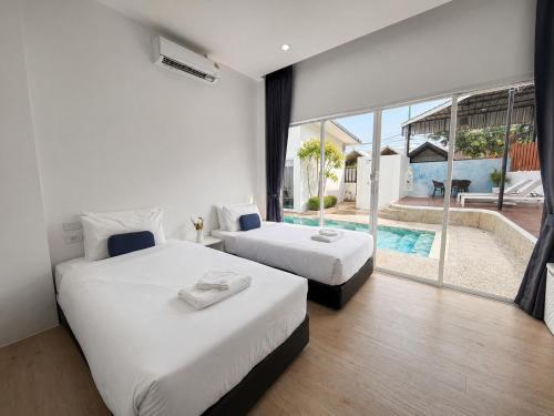 two beds in a hotel room with a swimming pool at A&J Holiday Villa in Ban Na Bon