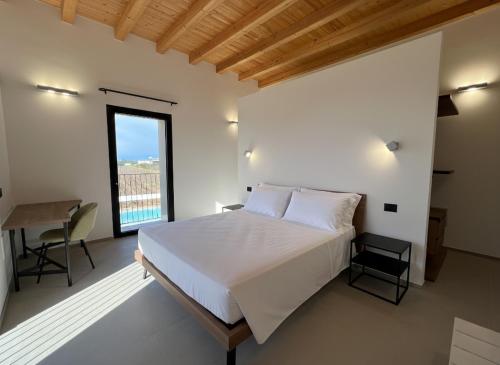 a bedroom with a bed and a table and a window at Giù al Vigneto in Leporano