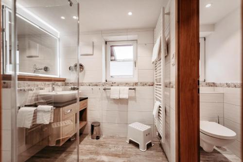 a white bathroom with a sink and a toilet at Bergblick - der Gasthof in Riezlern