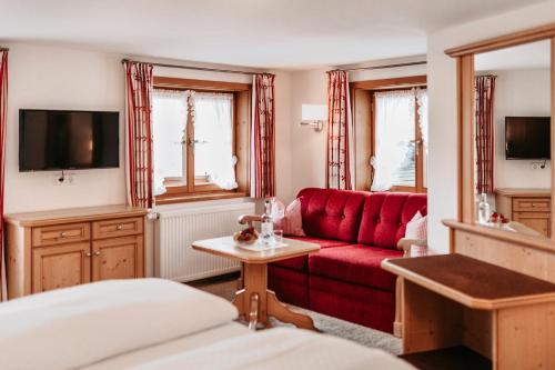 a living room with a red couch and a tv at Bergblick - der Gasthof in Riezlern
