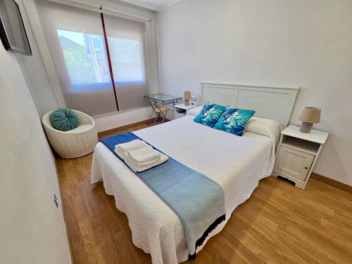 a bedroom with a bed with blue pillows and a window at Playa Jardin Boiro in Boiro