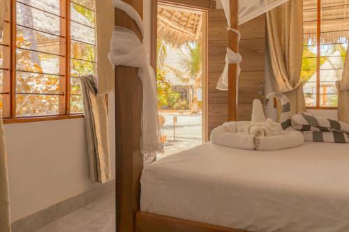 a bedroom with a bed in a room with windows at Sunset Mkuu Boutique Hotel in Michamvi