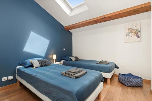 two beds in a room with blue walls and wooden floors at 10 Rue de la Rampe in Cannes