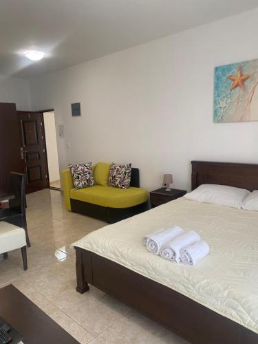 a bedroom with a bed and a yellow couch at Apartments Delfin in Bar