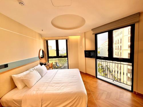 a bedroom with a large bed and two windows at The Sol Hotel in Phú Quốc