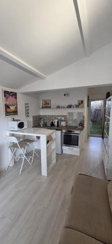 a large white kitchen with a table and a couch at Studio indépendant 2 personnes in Le Pradet