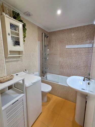 a bathroom with a sink and a toilet and a tub at Playa Jardin Boiro in Boiro