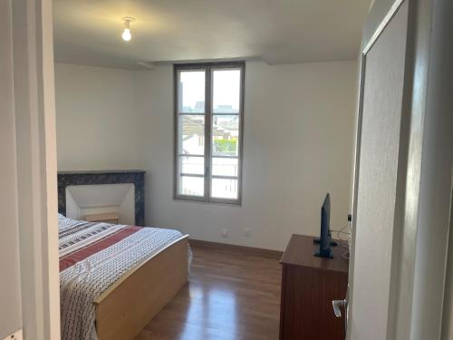 a bedroom with a bed and a tv and a window at Maison charmante in Le Mans