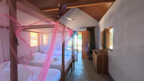 a bedroom with two bunk beds with pink ribbon at Happy Hippy Beach Cabanas Peanut Farm in Panama