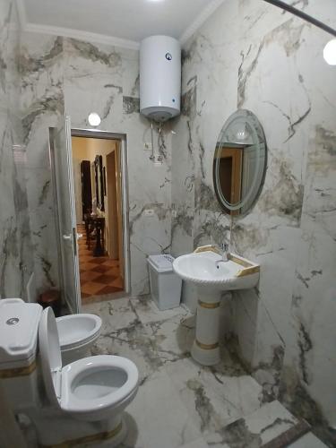 a marble bathroom with a toilet and a sink at Roland Palaj House in Shkodër
