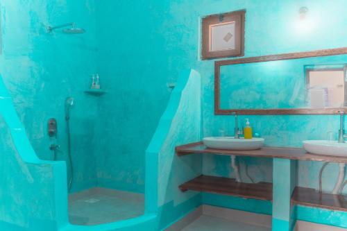 a blue bathroom with two sinks and a mirror at Sunset Mkuu Boutique Hotel in Michamvi