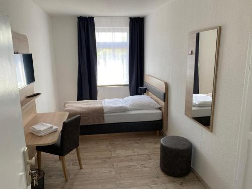 a bedroom with a bed and a desk and a mirror at Voigt's Hofpension GbR in Zahna-Elster