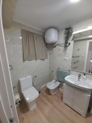 a bathroom with a white toilet and a sink at Alojamiento El Sevillano in Cullera