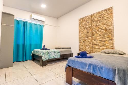 a bedroom with two beds and blue curtains at Cahuita Apartment by Angie in Cahuita