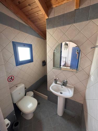 a bathroom with a toilet and a sink and a mirror at LifeHouse in Agia Pelagia