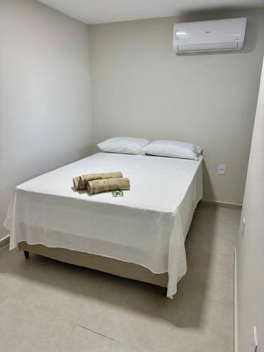 a white bedroom with a bed with towels on it at No centro, em frente à praça in Eunápolis