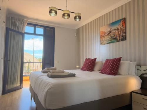 a bedroom with a large white bed with a window at Villa Feliz 44 in Meloneras