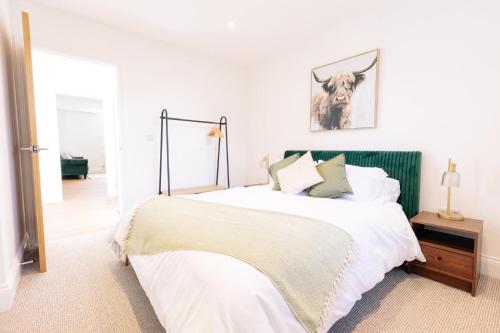 a white bedroom with a bed with a antelope picture on the wall at The Spa Town Loft in Buxton