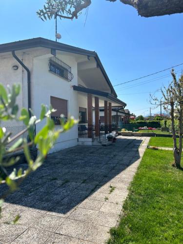 a white building with a porch and grass at AlMi House - Colline del Prosecco in Soligo