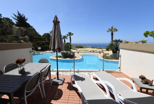a patio with a table and an umbrella and a pool at Hal Saghtrija - Gozo Hideaways in Żebbuġ