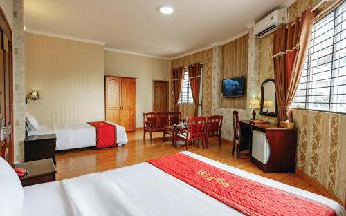 a hotel room with two beds and a table and chairs at Khách Sạn Long Xuyên in Long Xuyên