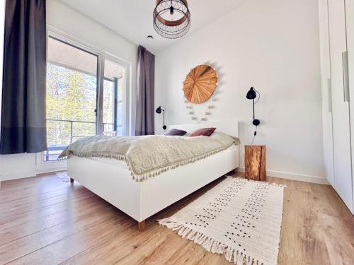 a white bedroom with a bed and a window at Apartament Nieznany Bór in Hajnówka