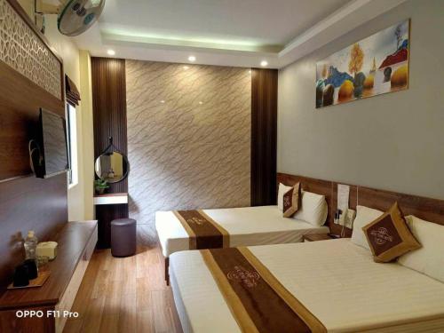 a hotel room with two beds and a television at Ngọc Tùng Hotel in Ha Long