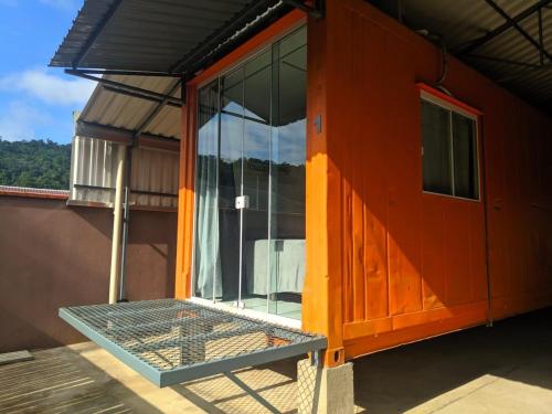 an orange house with a bed in front of it at Condomínio Containers está localizado a 900m do centro de Morretes, local calmo e em meio a mata Atlântica in Morretes