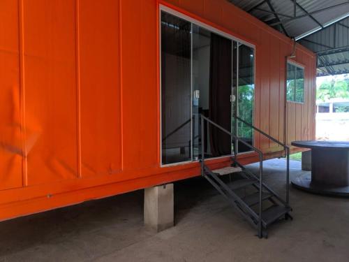 an orange building with a glass door and a staircase at Condomínio Containers está localizado a 900m do centro de Morretes, local calmo e em meio a mata Atlântica in Morretes