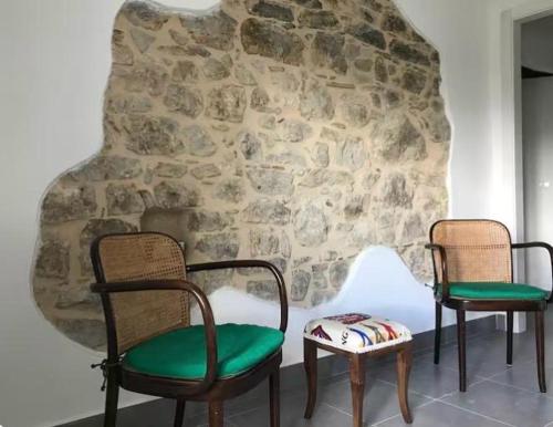 a room with three chairs and a stone wall at Casa Sirolli in Archi