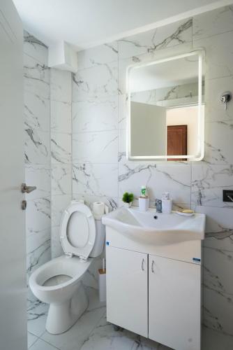 a white bathroom with a toilet and a sink at Josahouse in Bjeluša