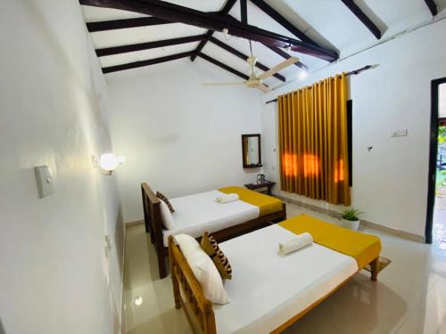 two beds in a room with white walls at Lakeside Haven Resort in Habarana