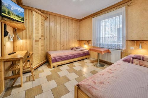 a bedroom with two beds and a desk and a window at Domki - Pod Smerkami in Szklarska Poręba