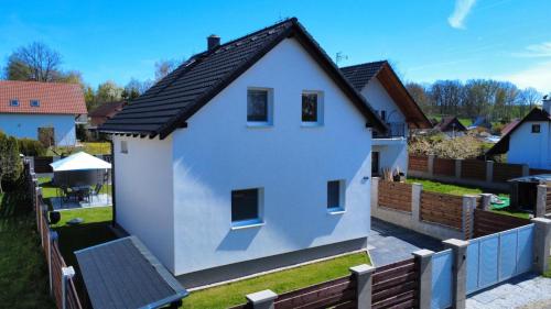 a white house with a black roof in a yard at Vila Jesenice in Lipová