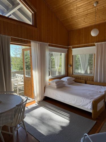 a bedroom with a bed and a table and windows at Miiluranta Villas in Haapamäki