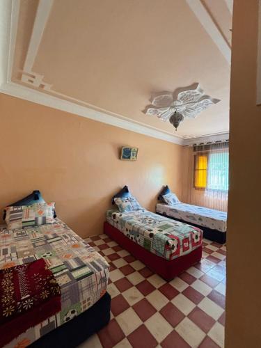 a bedroom with two beds and a checkered floor at casa chawni in Chefchaouen