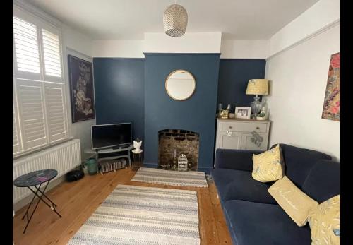 ein Wohnzimmer mit blauen Wänden und einem blauen Sofa in der Unterkunft Faversham cottage in Kent