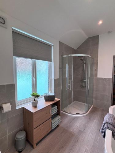 a bathroom with a shower and a wooden dresser at Cockle Cottage in The Mumbles