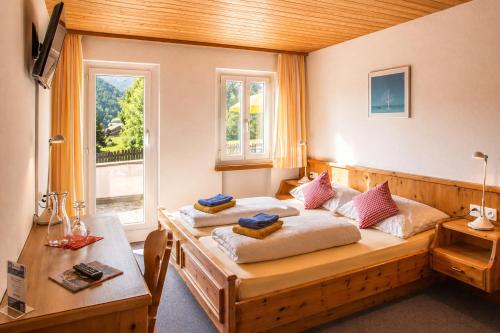 a bedroom with a bed and a table and a window at Hotel Chalamandrin in Ftan