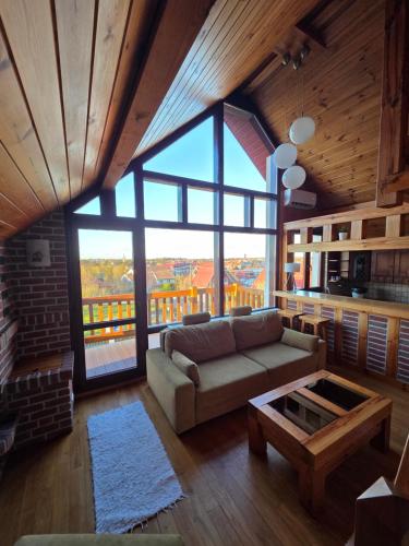 a living room with a couch and a large window at Mazurski Zakątek-Apartamenty in Mikołajki