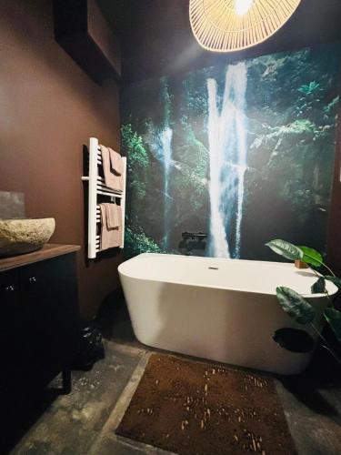 a bath tub in a bathroom with a painting on the wall at Expérience Balinaise à Amiens in Amiens