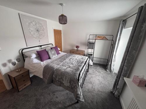 a bedroom with a bed with purple pillows and a mirror at Cockle Cottage in The Mumbles