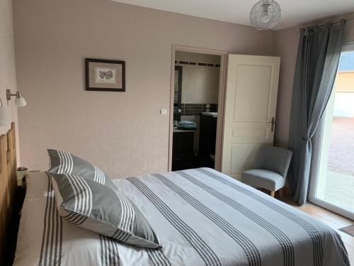 a bedroom with a bed and a chair and a window at La brèche fleurie in Cricquebœuf