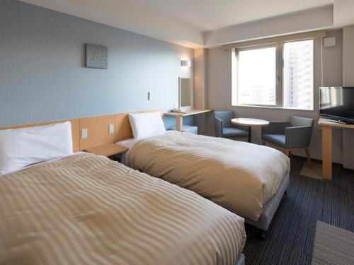 近江八幡市にあるコンフォートイン近江八幡のベッド2台とテレビが備わるホテルルームです。
