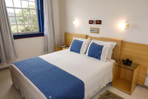 a bedroom with a blue and white bed and a window at Pousada do Garimpo in Diamantina