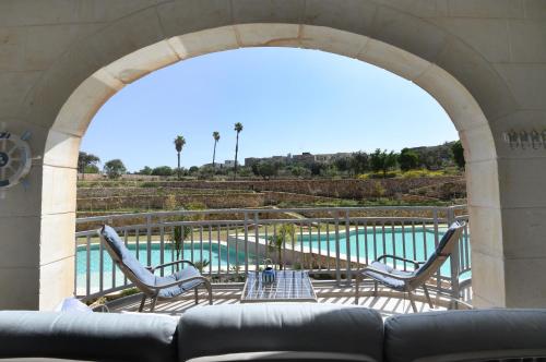a patio with a couch and chairs and a pool at Hal Wardija - Gozo Hideaways in Qala