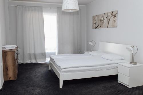 a white bedroom with a white bed and a window at Rakhiv Hotel & Apartments in Rakhiv