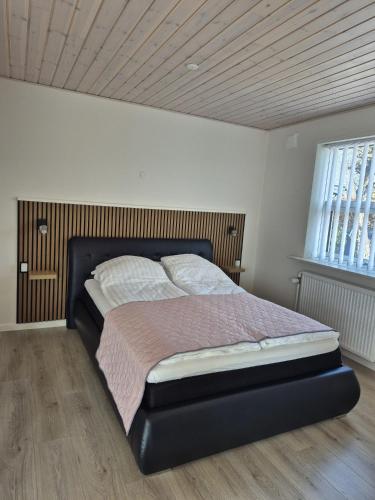 a bed in a bedroom with a wooden ceiling at Annes Hus in Rødekro