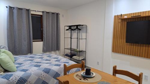 a bedroom with a bed and a table and a tv at Studio prático e tranquilo em Jacobina in Jacobina